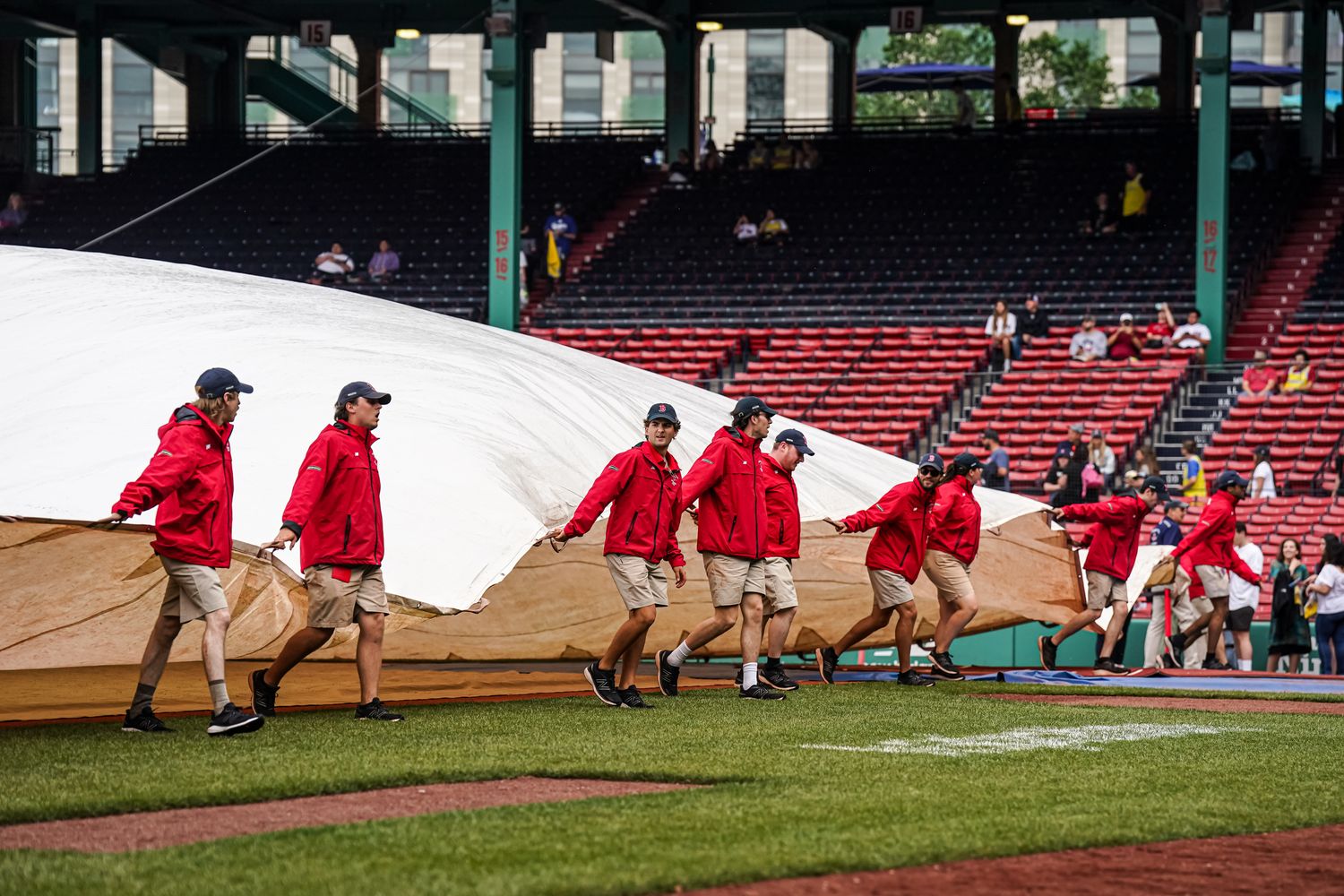 Jun 14, 2023; Boston, Massachusetts, USA; The Boston Red Sox field crew cover the field in anticipation of rain before the start of the game against the Colorado Rockies at Fenway Park.